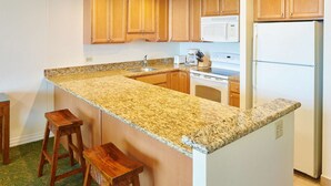 A kitchen with granite countertops, wooden cabinets, a white refrigerator, and a built-in oven.