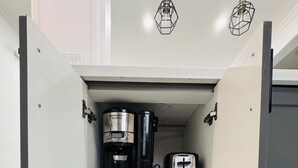Ein Küchenschrank mit Kaffeemaschine, Toaster und Wasserkocher.