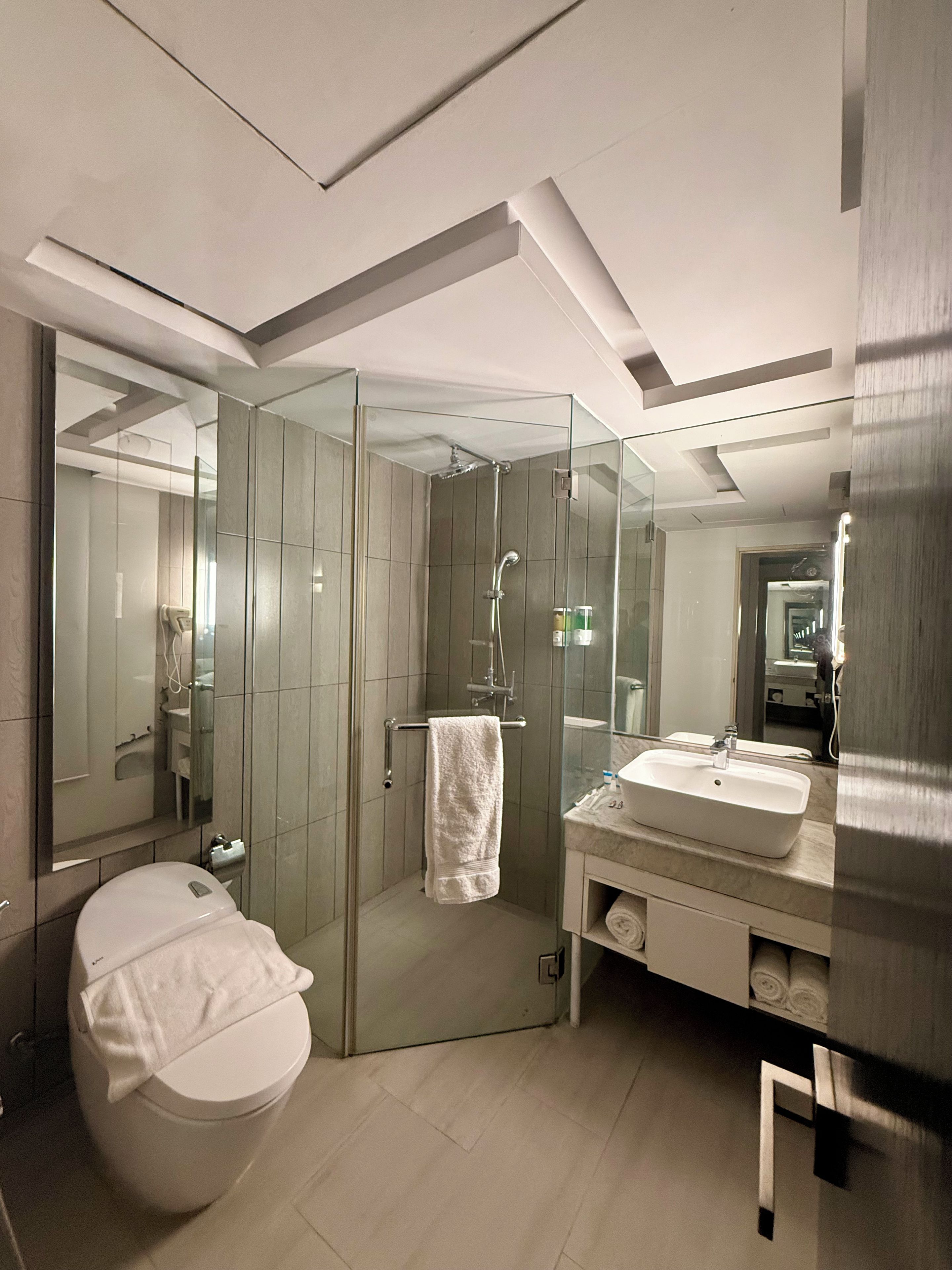 Une salle de bain moderne avec une douche à parois de verre, des toilettes blanches et un meuble-lavabo.