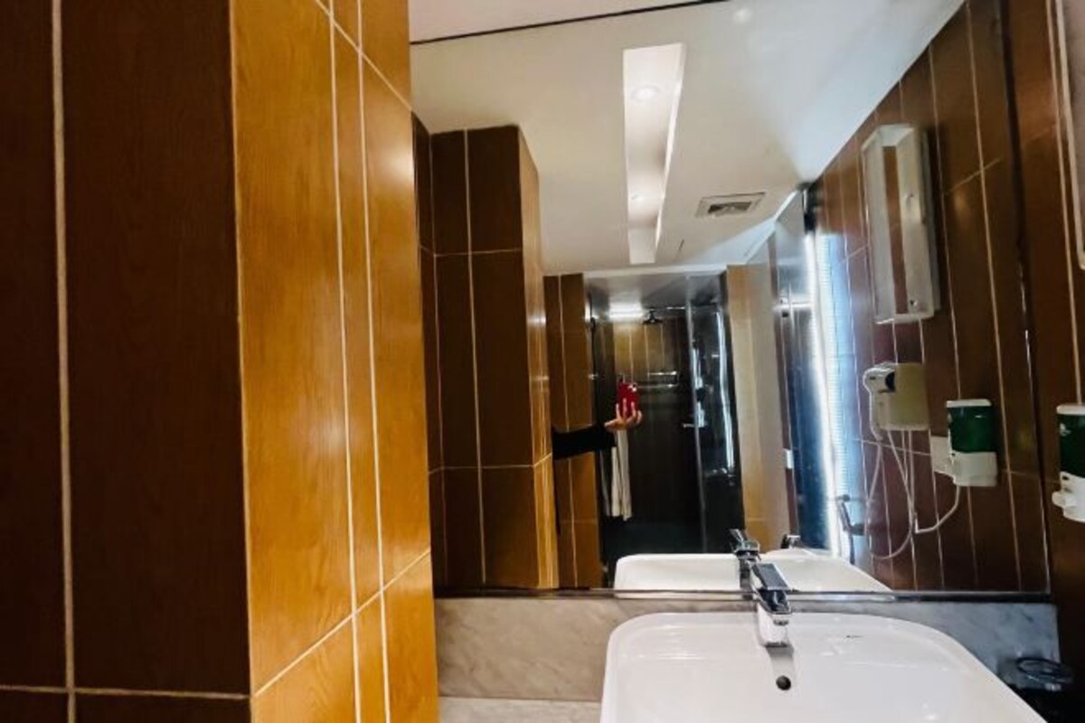 A modern bathroom with a large mirror, a sink, and a shower area.