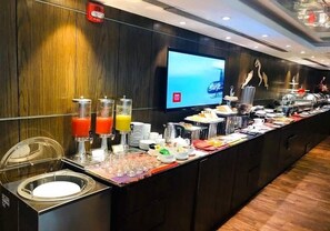 Dispositiu de buffet amb una varietat d'aliments i begudes, una pantalla de televisió i un detector de fum a la paret.