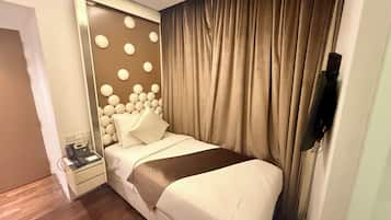 A hotel room with a bed, a bedside table, a telephone, and a wall-mounted TV.