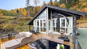 Ein modernes Haus mit Terrasse, Sitzgelegenheiten im Freien und einer Glasveranda.