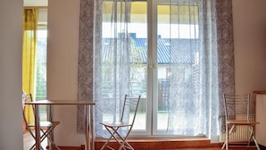 Una habitación con puerta corredera de vidrio, una mesa y dos sillas.