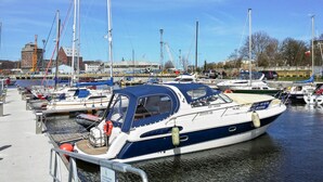 Un puerto deportivo con varias embarcaciones amarradas, incluyendo un barco de motor azul y blanco con cabina.