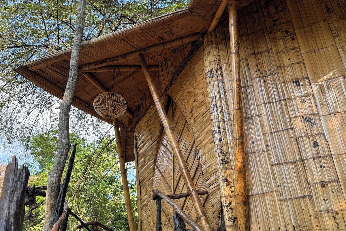 A bamboo structure with a sloped roof and wooden beams.