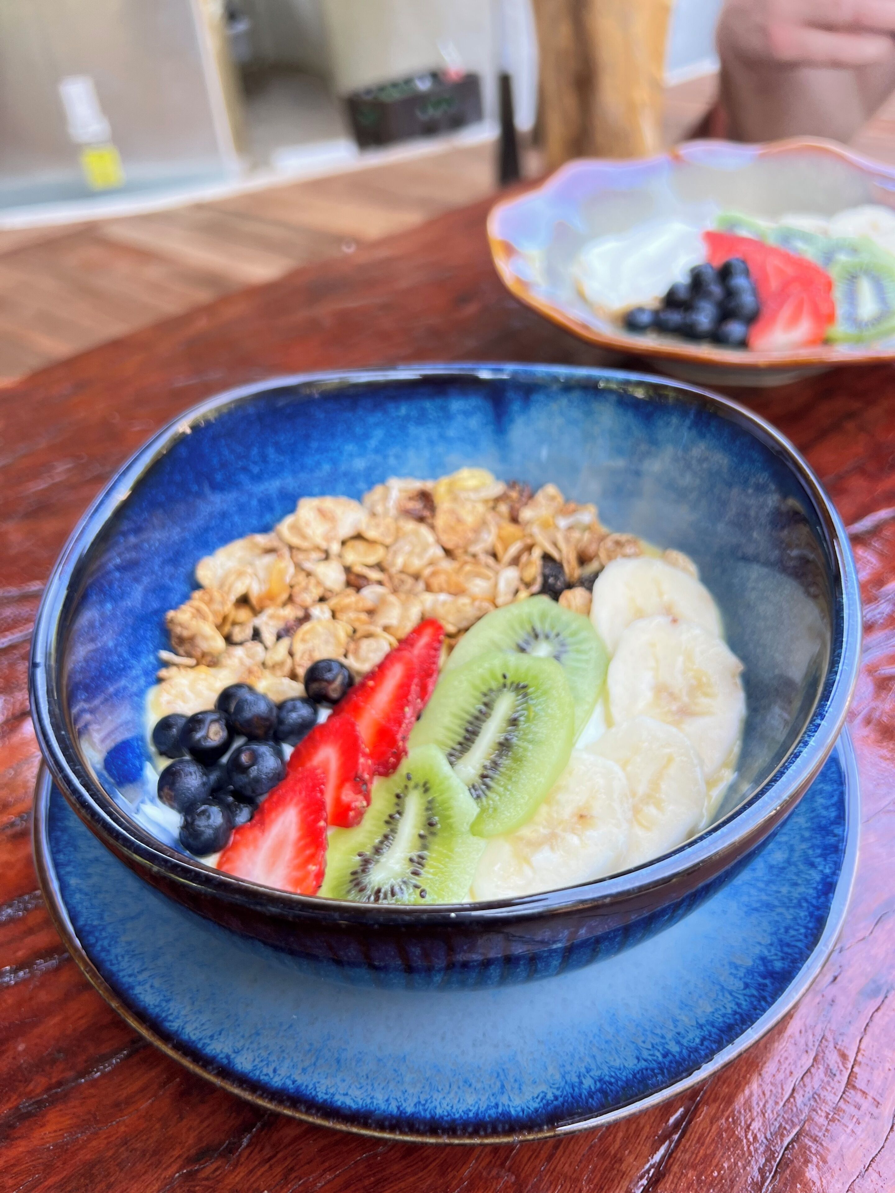 Een kom havermout met fruit en granola op een blauw bord.