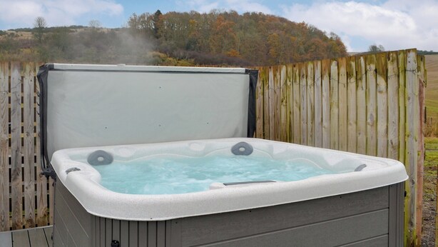 A hot tub with a wooden fence and a hill in the background. - 3 bedroom accommodation in Blairgowrie (Blairgowrie)