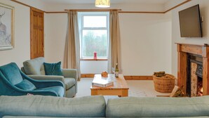 A living room with a sofa, armchairs, a coffee table, a fireplace, and a television. - 3 bedroom accommodation in Blairgowrie (Blairgowrie)