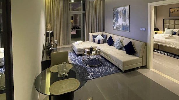 A modern hotel room with a sofa, a dining table, and a bed. - Damac Majestine VIP (Dubai)