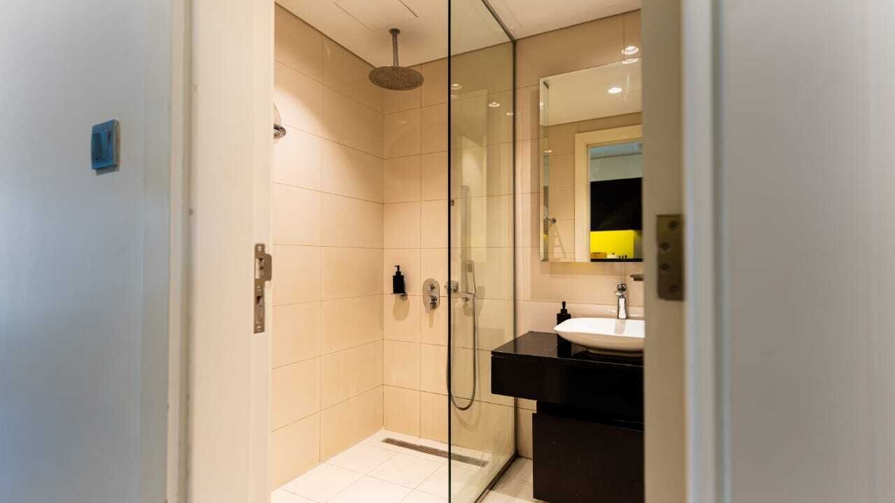 Een moderne badkamer met een douchecabine van glas, een zwart wastafelmeubel en een spiegel erboven.