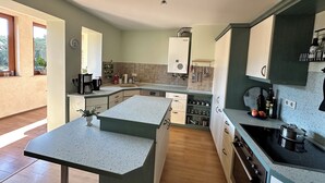 Een moderne keuken met een centraal eiland, inbouwapparatuur en veel werkruimte.