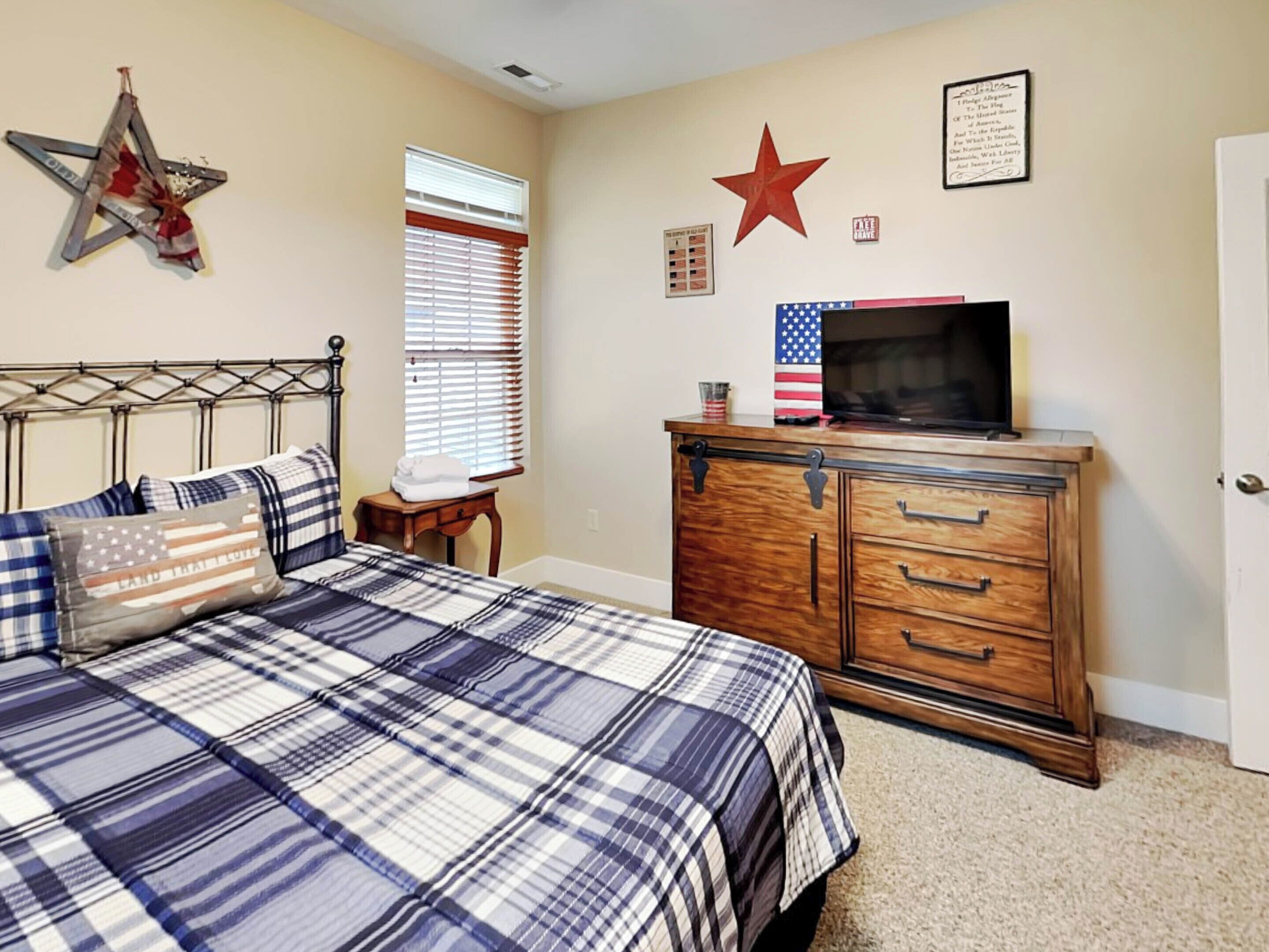 Una camera da letto con un letto, una cassettiera e decorazioni a parete, tra cui stelle e una bandiera americana.