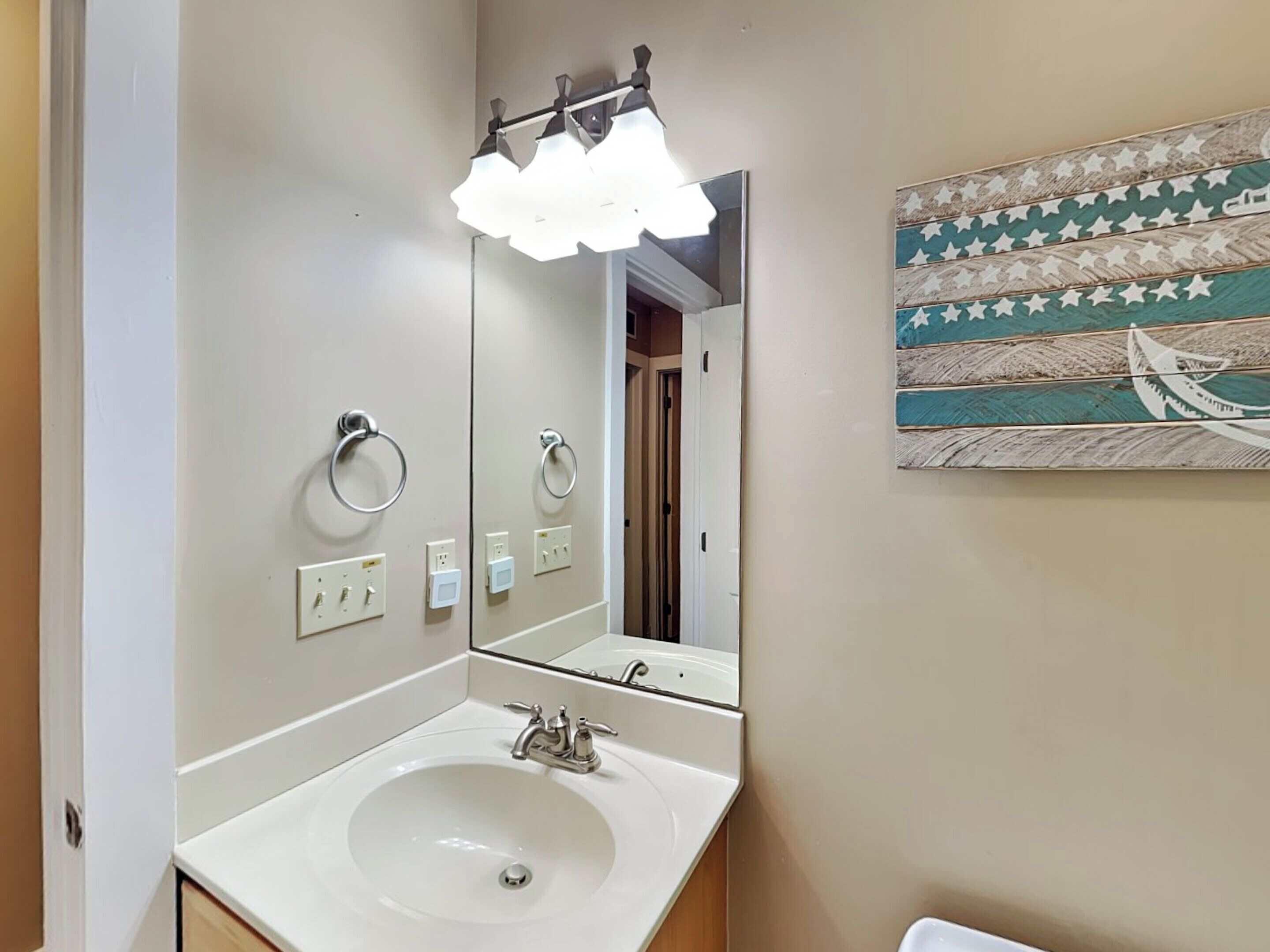 A bathroom with a white sink, a mirror, and a towel ring.