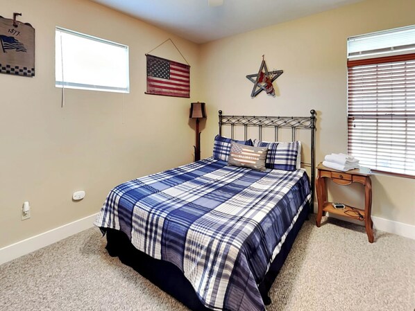 Quarto com cama, bandeira americana, enfeite de estrela e janela com persianas.