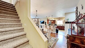 A spacious kitchen with a central island, wooden flooring, and a staircase leading to an upper level. - Bluebeary Retreat by Taylor Made Deep Creek (McHenry)