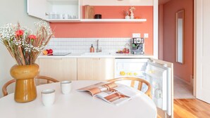 A modern kitchen with white cabinets, a white countertop, and a built-in coffee machine.
