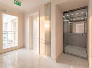 A clean, modern elevator with a metallic finish, a glass door, and a handrail. - TurnKey | Vineyard Terrace Two-Level Apartment (Praha 2)