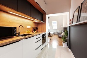 Cocina moderna con microondas, pileta y encimera de madera.