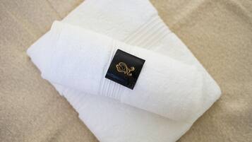 Ein ordentlich gefaltetes weißes Handtuch mit einem schwarzen Etikett, das ein goldenes Wappen zeigt.