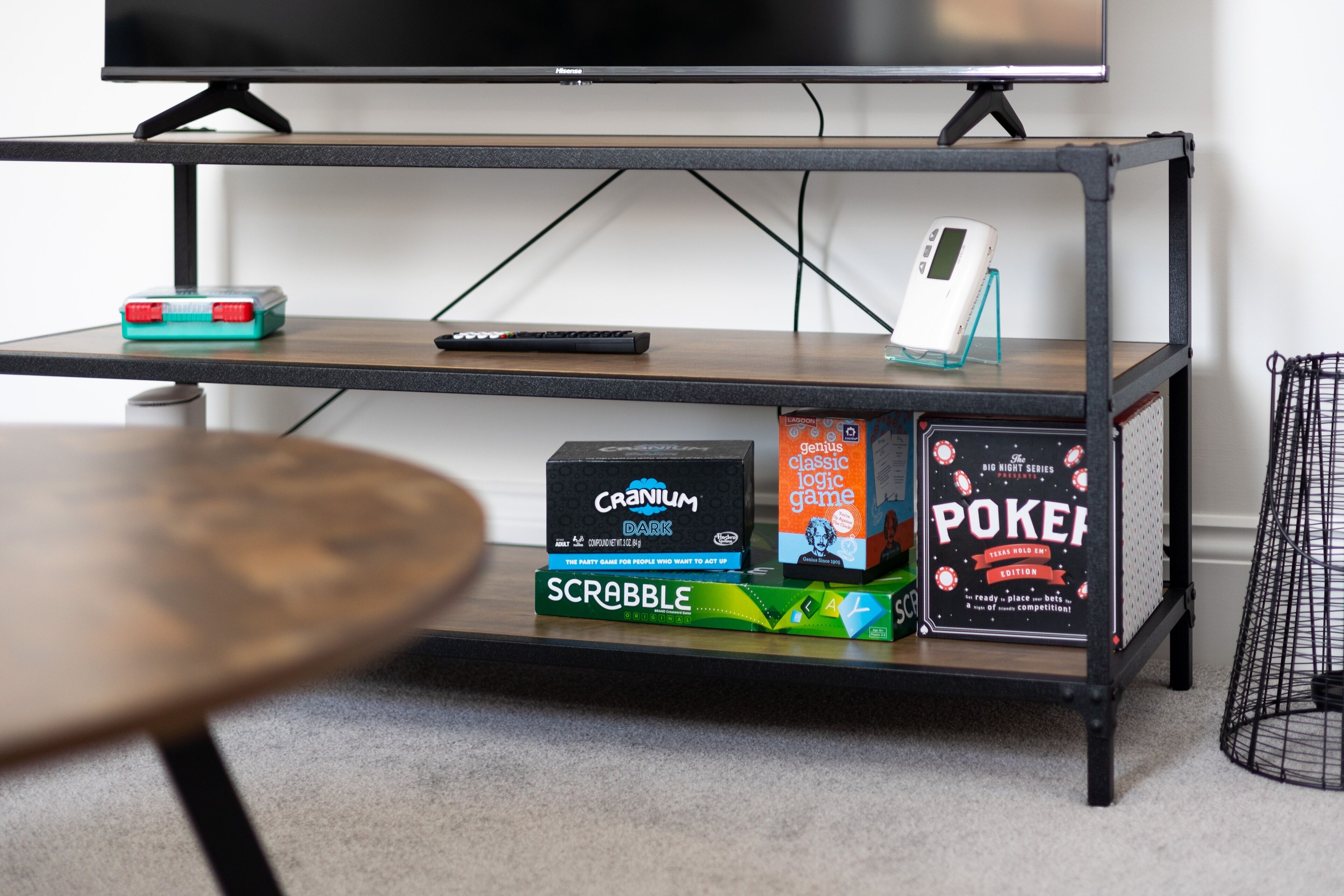 Ein TV-Schrank mit Fernbedienung, einer Digitaluhr und Gesellschaftsspielen wie Scrabble und Pictionary.