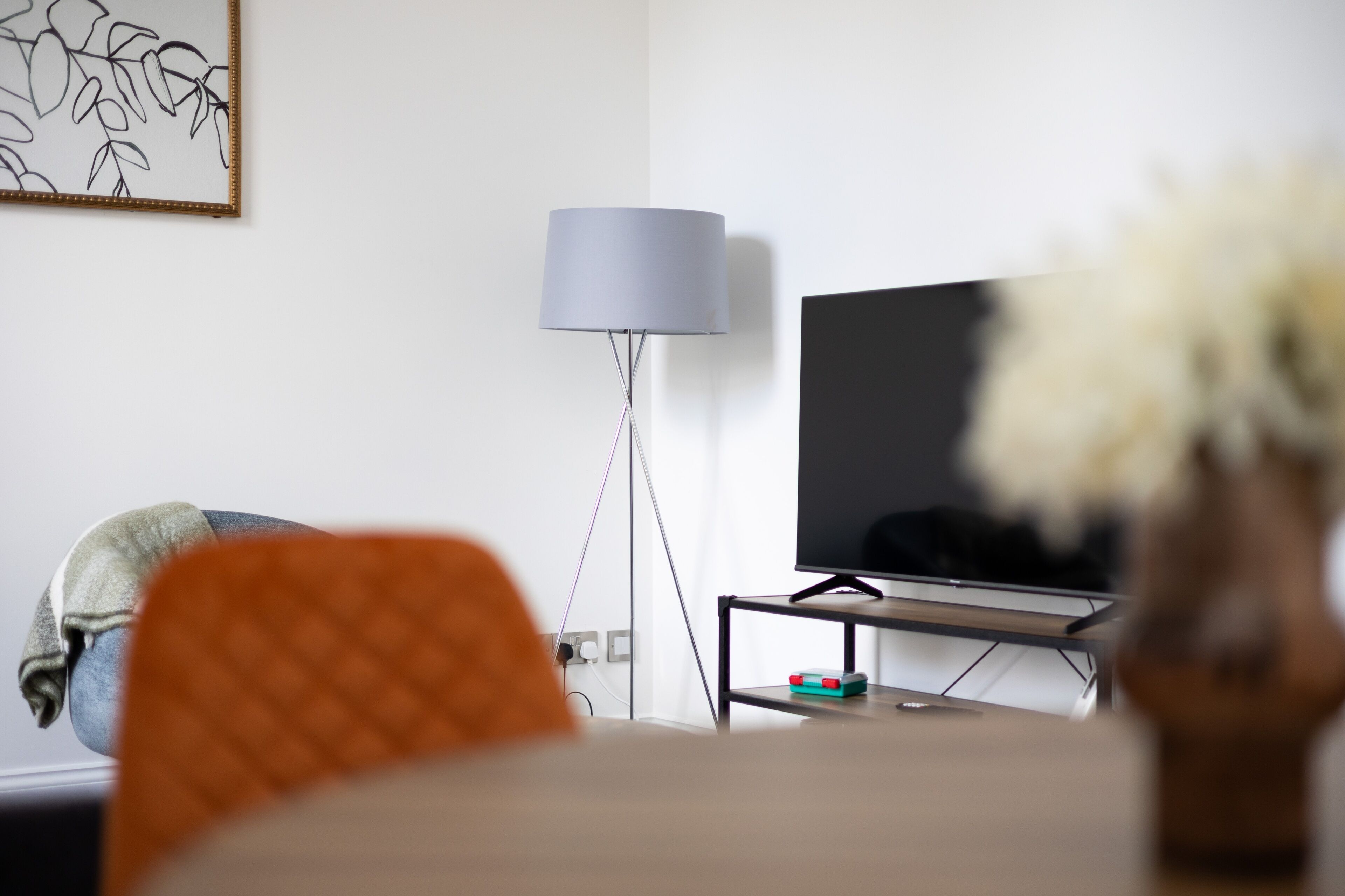 A living room with a television, a lamp, and a painting on the wall.
