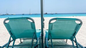 A beach umbrella with two green chairs under it, overlooking a calm sea with boats. - The Lotus Room, Carlisle Bay, Eden On The Sea  (Bridgetown)
