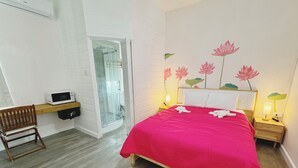 A hotel room with a bed, a wooden chair, a microwave, a glass shower, and a wall with a lotus flower mural. - The Lotus Room, Carlisle Bay, Eden On The Sea  (Bridgetown)