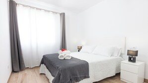 Une chambre à coucher bien rangée, avec un lit, des lampes de chevet, une table de nuit et une fenêtre avec des rideaux.