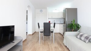 Un salon moderne doté d’un téléviseur à écran plat, d’un canapé et d’un coin repas avec des chaises et une table.