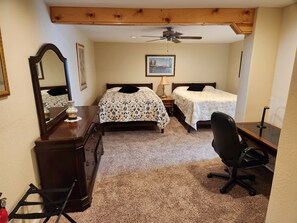 Classic bedroom with two single beds, a wooden dresser, and a desk for a comfortable workspace.