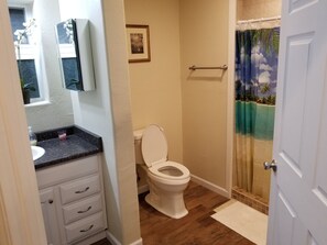 Bathroom features a toilet, sink, and shower with a tropical design.