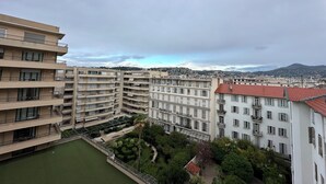 A multi-story residential building with balconies, a courtyard, and a view of a distant mountain range. -  Carre D’Or - Discover a unique address in the heart of Promenade des Anglais.  (Nice)