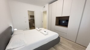 Een moderne slaapkamer met een bed, een televisie en een kledingkast.