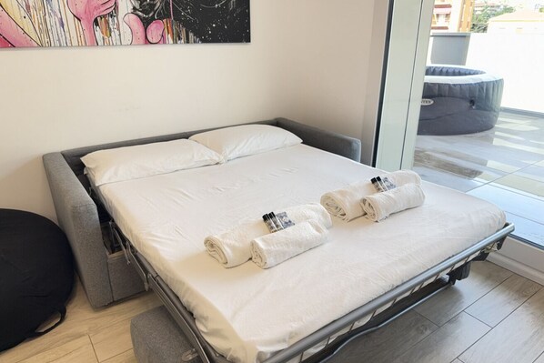 Habitación de hotel moderna con cama, almohadas y toallas enrolladas.