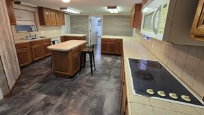 A kitchen with wooden cabinets, a central island, a built-in stove, and a refrigerator.