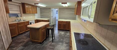 A kitchen with wooden cabinets, a central island, a built-in stove, and a refrigerator.