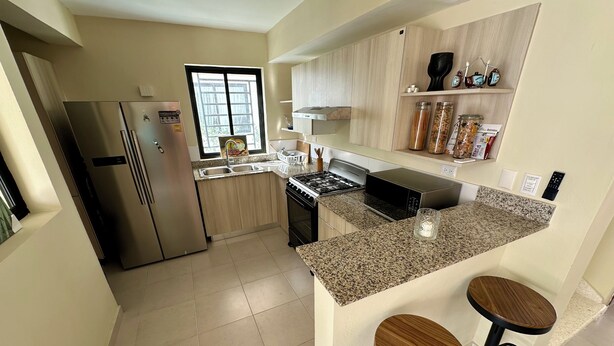 A modern kitchen with stainless steel appliances, a granite countertop, and wooden bar stools.