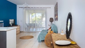 Una sala de estar moderna con un gran ventanal corredizo que da a un espacio exterior, una mesa de comedor de madera y una pared azul decorativa.