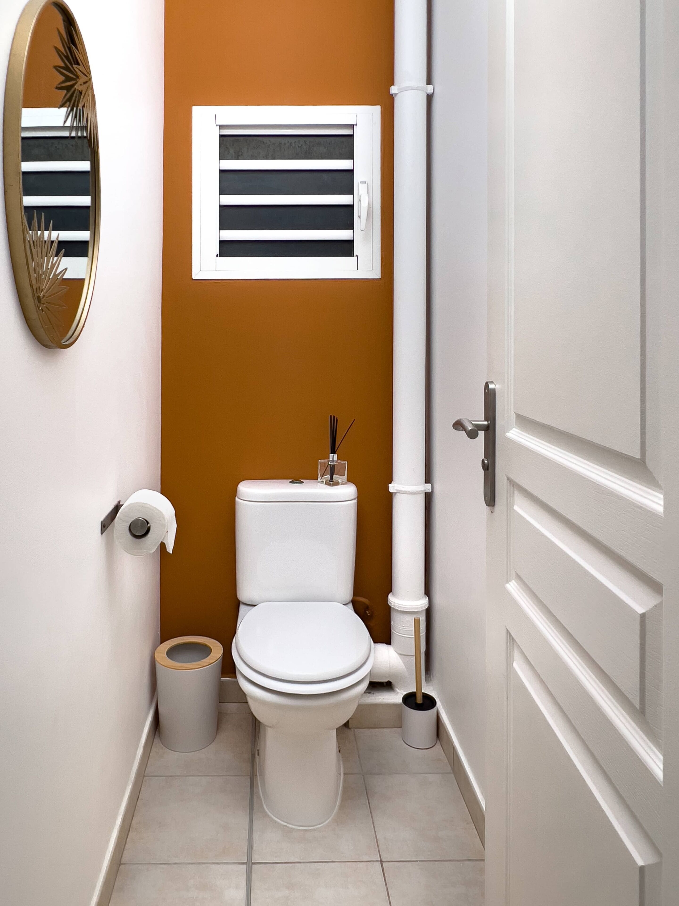 A compact bathroom with a toilet, a roll of toilet paper, a bidet, and a small trash bin.