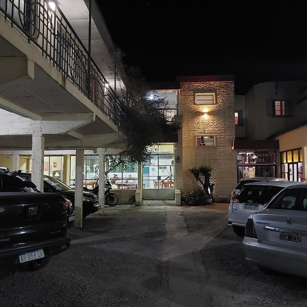A hotel entrance with a brick facade, a covered parking area, and a visible restaurant in the background.