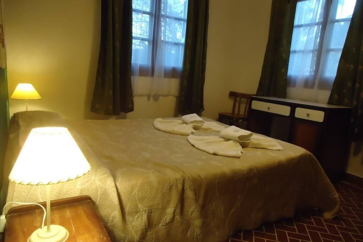 Ein Hotelzimmer mit Bett, Schreibtisch, Lampe und Vorhängen.