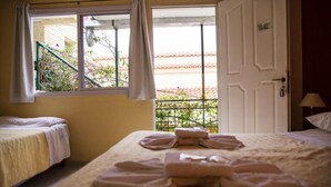 Ein Hotelzimmer mit zwei Betten, einem Fenster mit Vorhängen und Blick auf einen Garten.