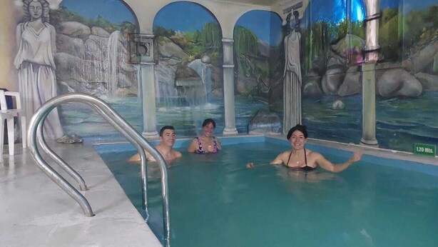 Ein Hallenbad mit Wandgemälde einer Wasserfall und Statuen.