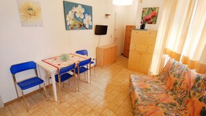 A compact living space with a dining area, a sofa, and a TV.