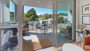 A modern interior with a glass door leading to a balcony with a view of a parking area and greenery. - Malthouse Lane City Apartment 4 with Stunning Hill Views in Nelson CBD (Nelson)