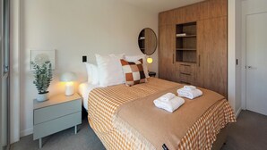A neatly arranged bedroom with a bed, bedside table, lamp, and a mirror. - Malthouse Lane City Apartment 4 with Stunning Hill Views in Nelson CBD (Nelson)