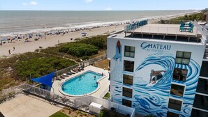 Un hotel con piscina, vista sulla spiaggia e un murale raffigurante un surfista.