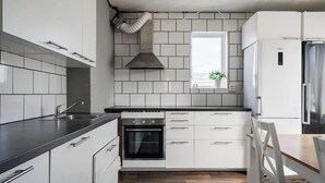 Une cuisine moderne avec des armoires blanches, un comptoir noir, un four encastré et une hotte de cuisinière en acier inoxydable.