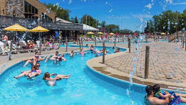 A public swimming pool with multiple lanes, lounge chairs, and umbrellas.